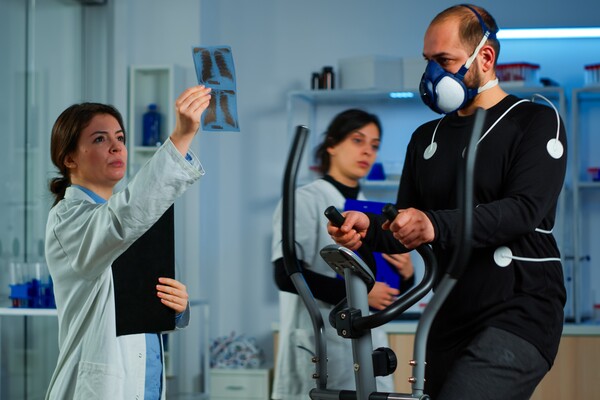 A imagem contém duas especialistas em Medicina Esportiva fazendo uma análise do raio x de um atleta.
